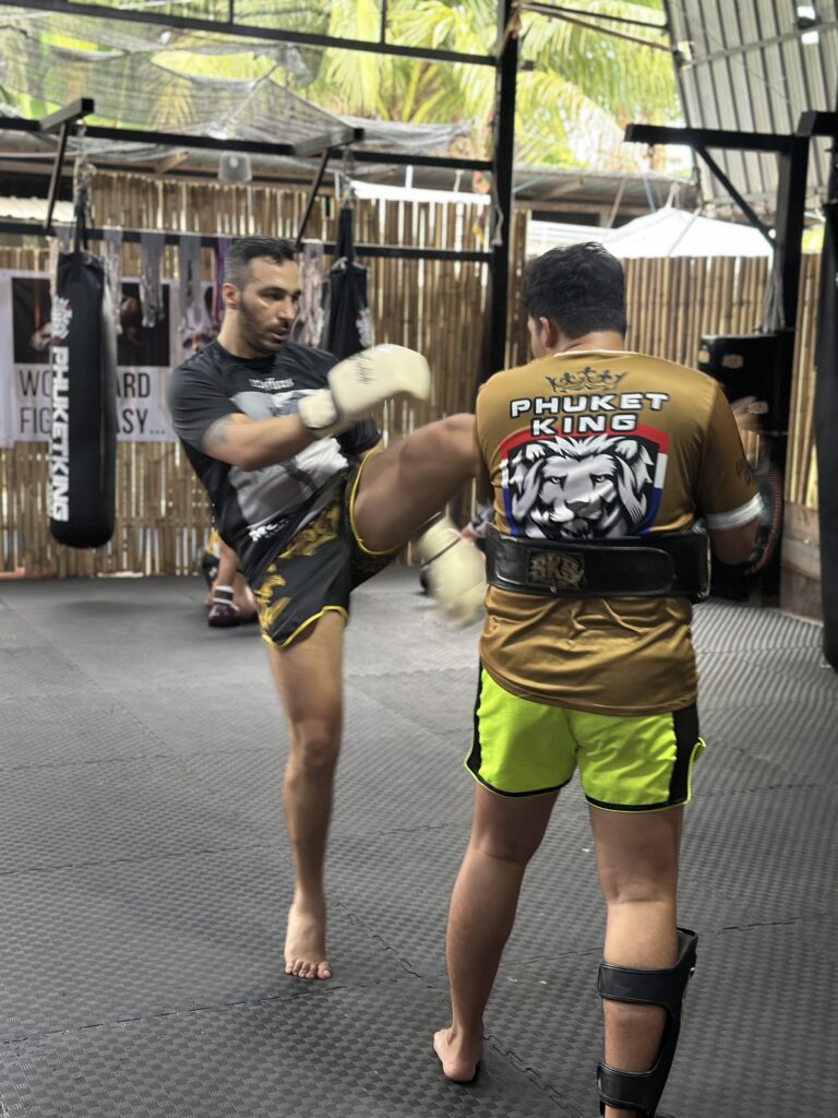 Trainer talking with a student one to one before a session. Alt text: Muay Thai trainer consultation with student at Phuket King Muay Thai Phuket 